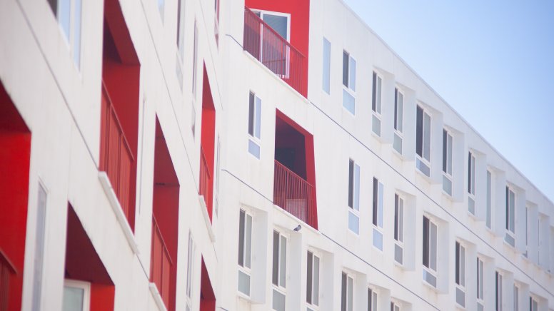 White exterior façade of a care home with occasional red-painted window walls